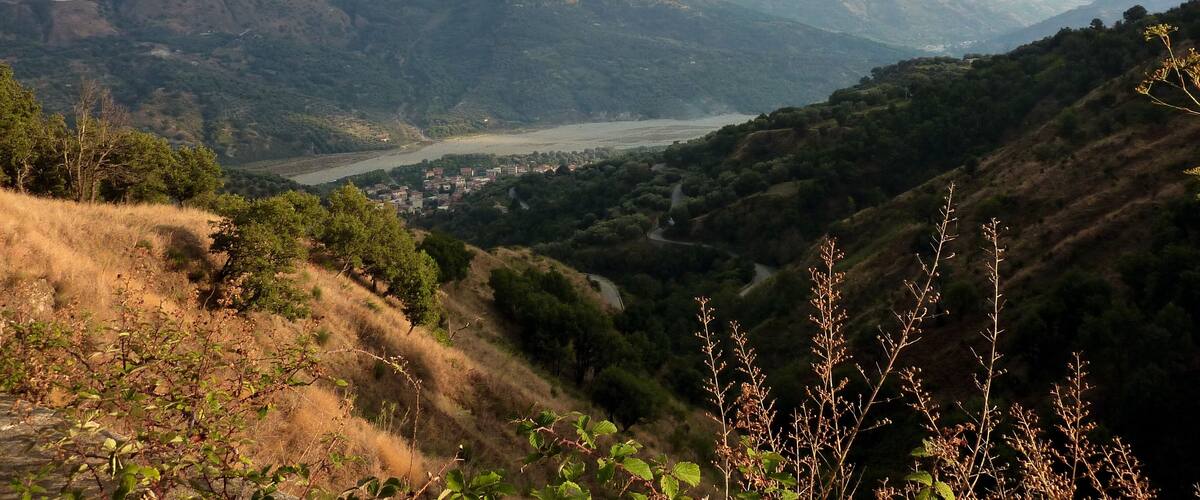 A mountainous landscape with a river valley and a town in the distance.