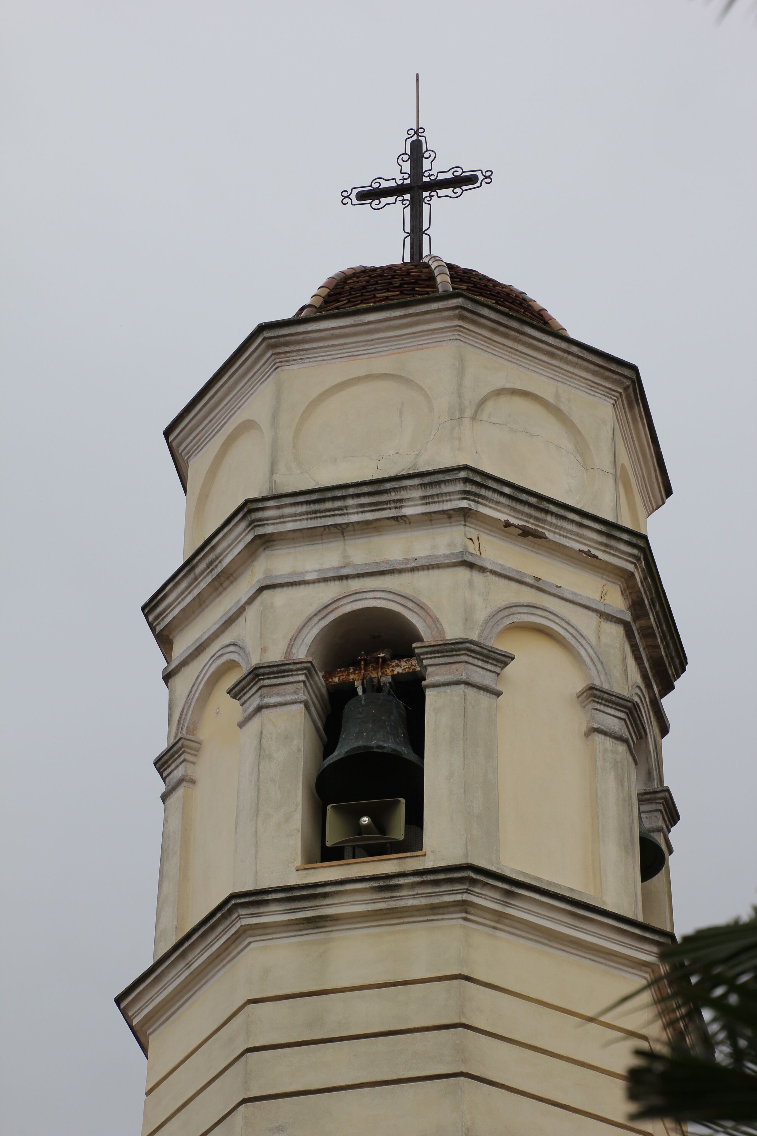 A church tower with a cross on top and a bell inside.