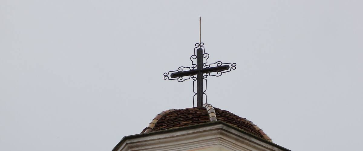 A church tower with a cross on top and a bell inside.