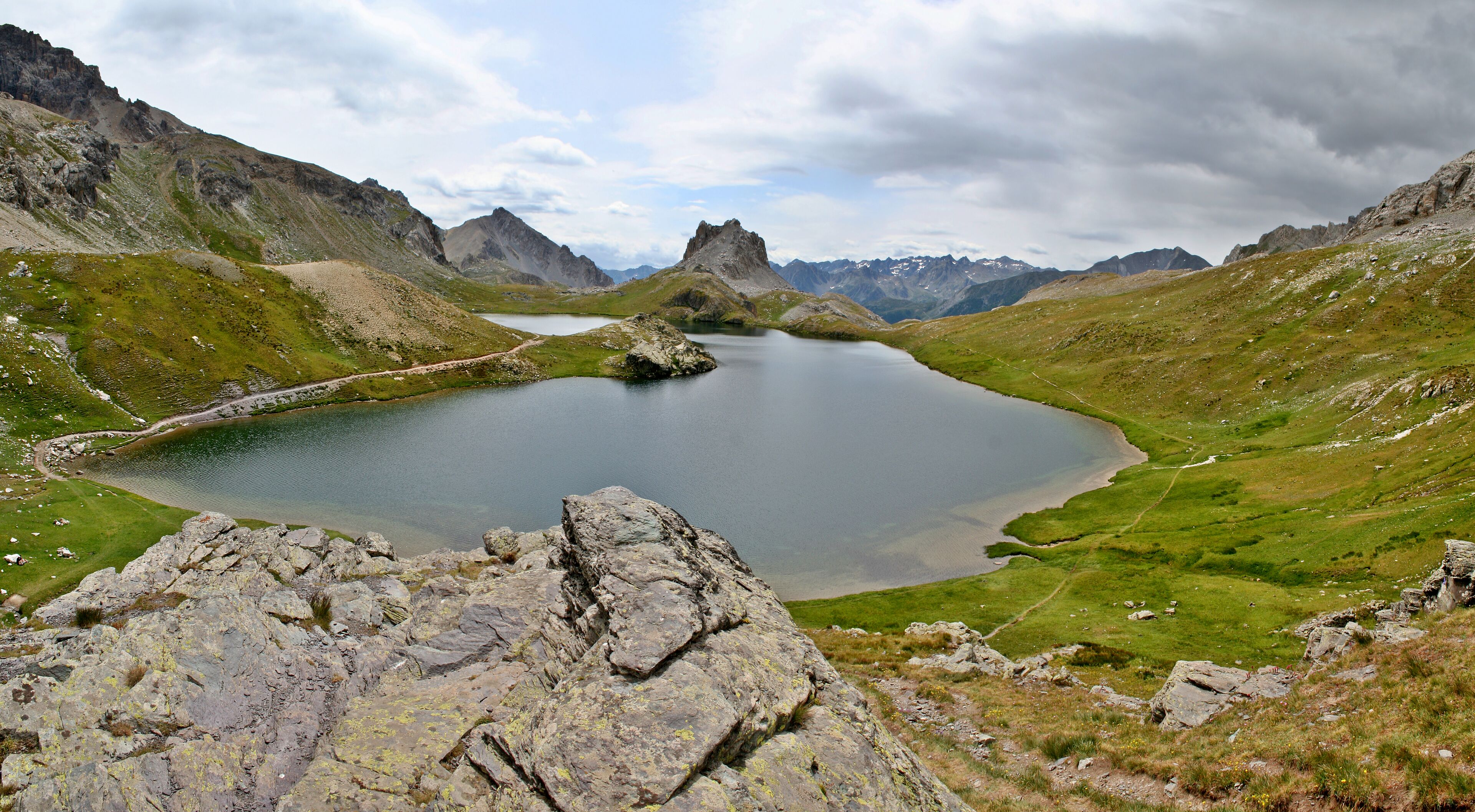 A mountain lake surrounded by rocky terrain and distant peaks.