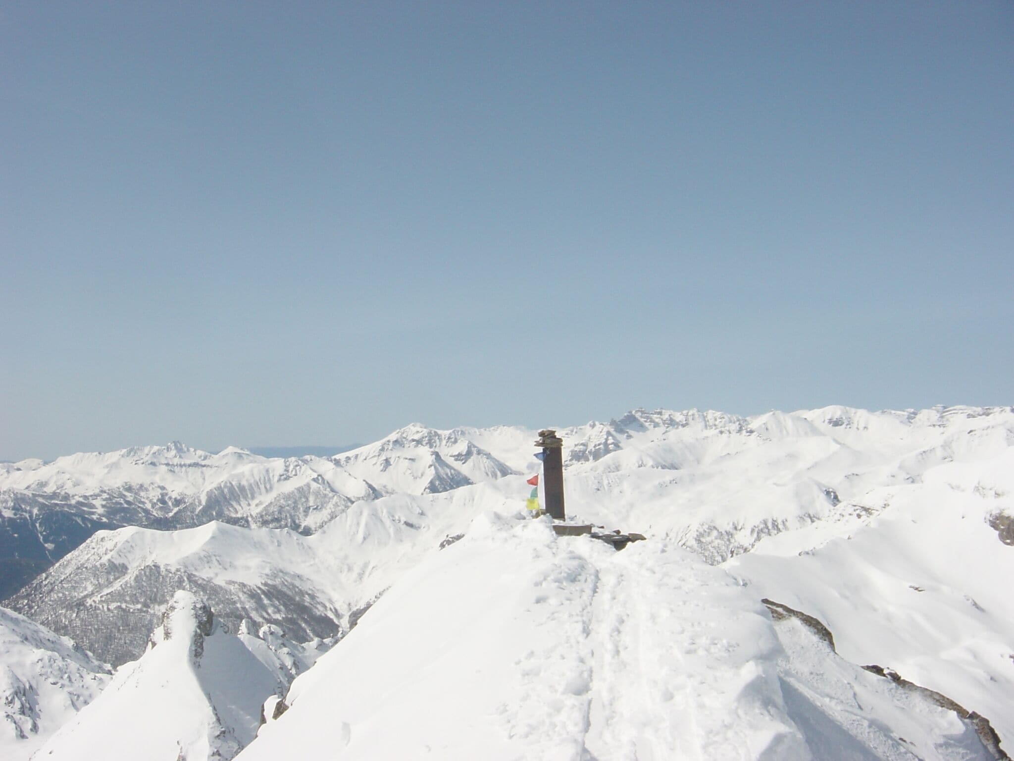 Ein mit Schnee bedeckter Berggipfel mit einer Fahnenmast und einer Flagge.