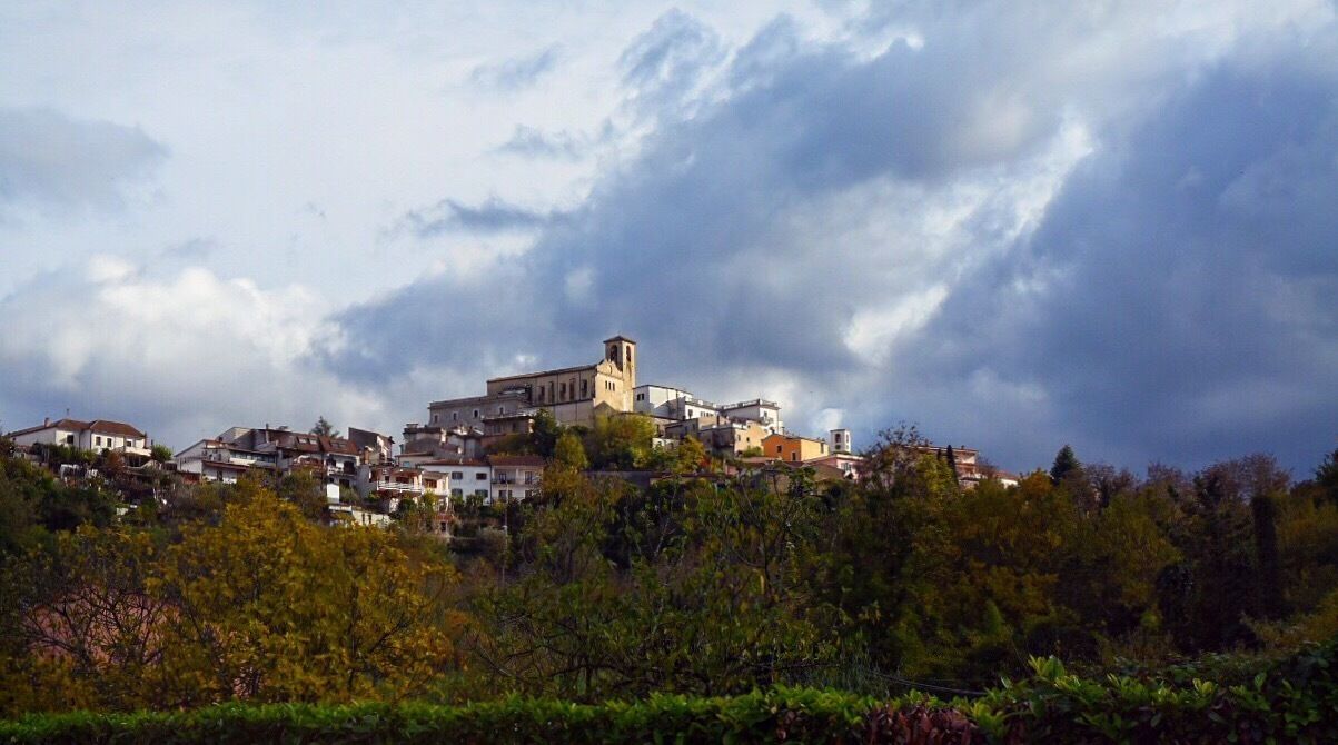 A town with a prominent church on a hill, surrounded by residential buildings and lush greenery.