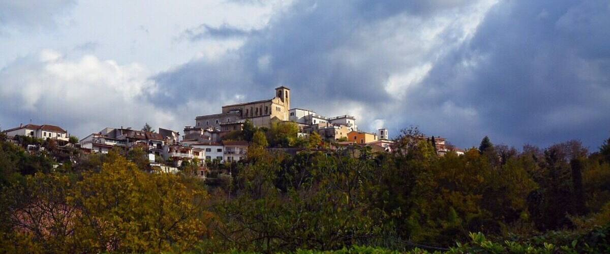A town with a prominent church on a hill, surrounded by residential buildings and lush greenery.