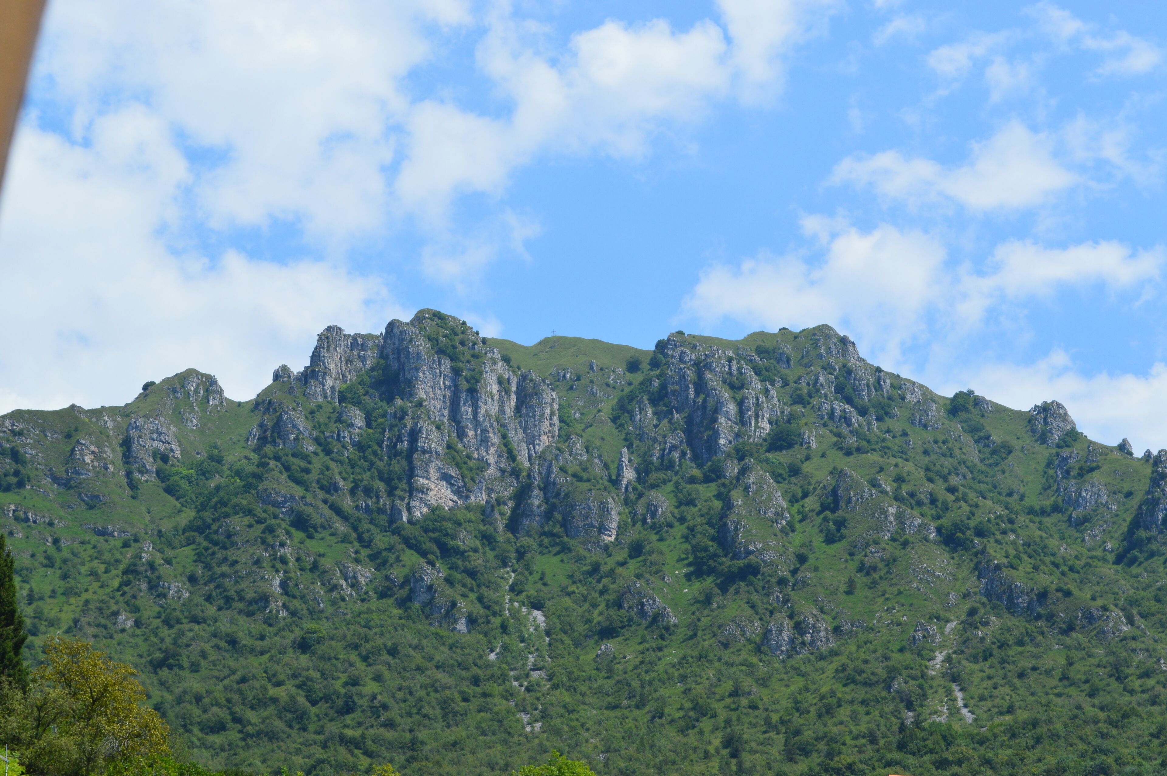 A mountain range with rugged cliffs and dense green vegetation.