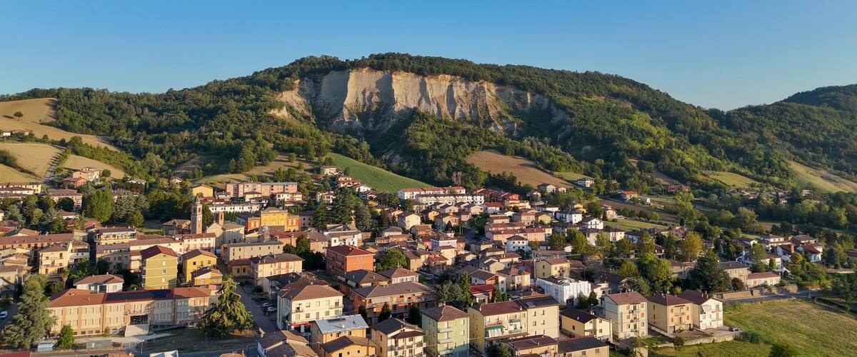A town nestled in a valley with a prominent cliff face in the background.