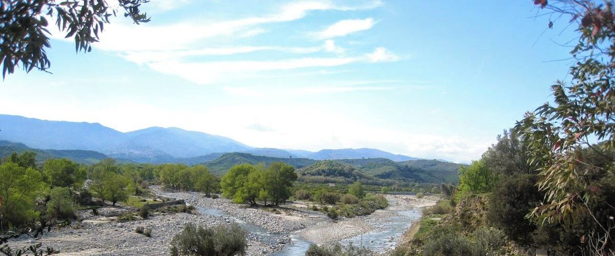 A river flowing through a valley with mountains in the background.