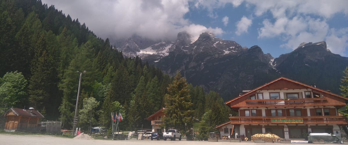 A mountain landscape with a wooden building in the foreground and a snow-capped peak in the background.