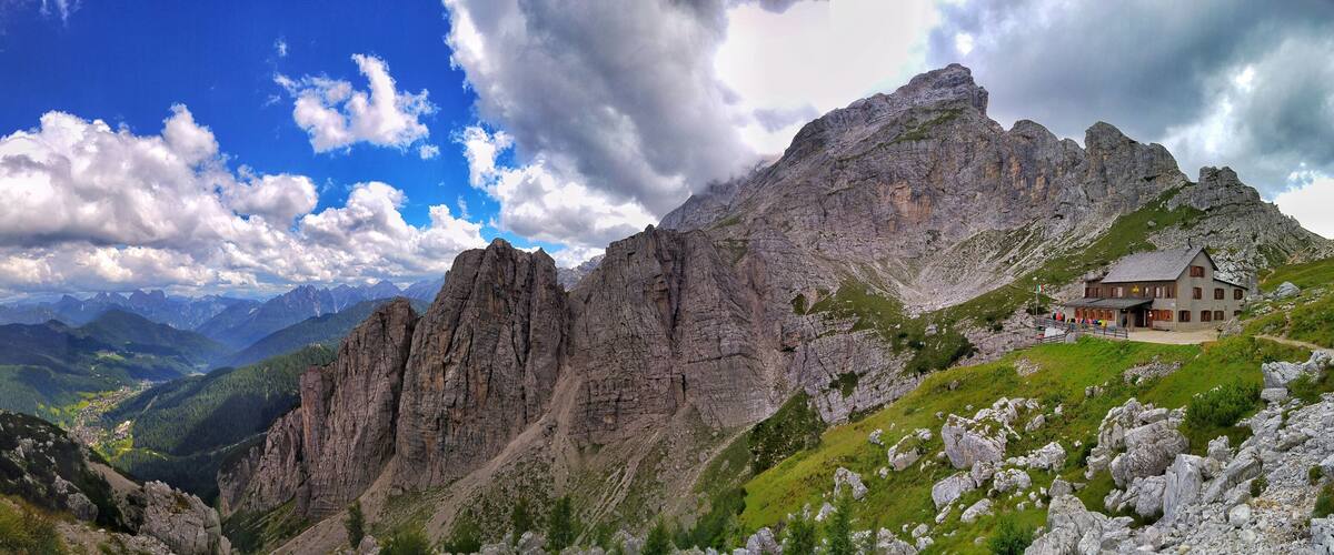 A mountain landscape with a rocky path, a small building, and a valley.