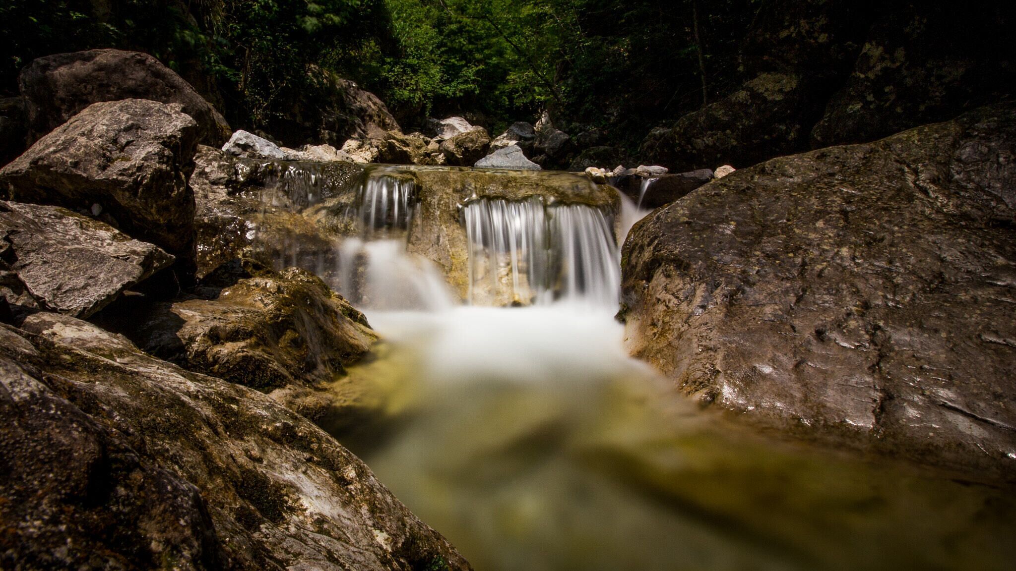 A waterfall surrounded by large rocks and dense forest.