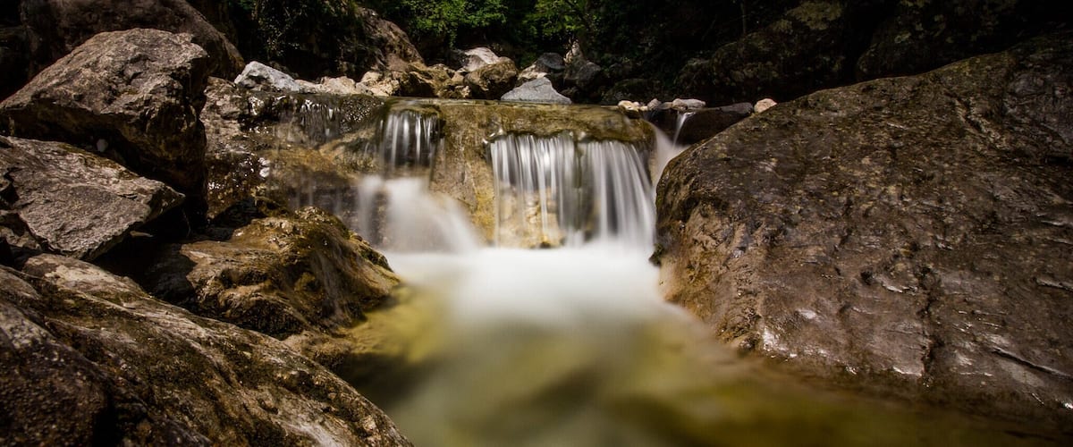 A waterfall surrounded by large rocks and dense forest.
