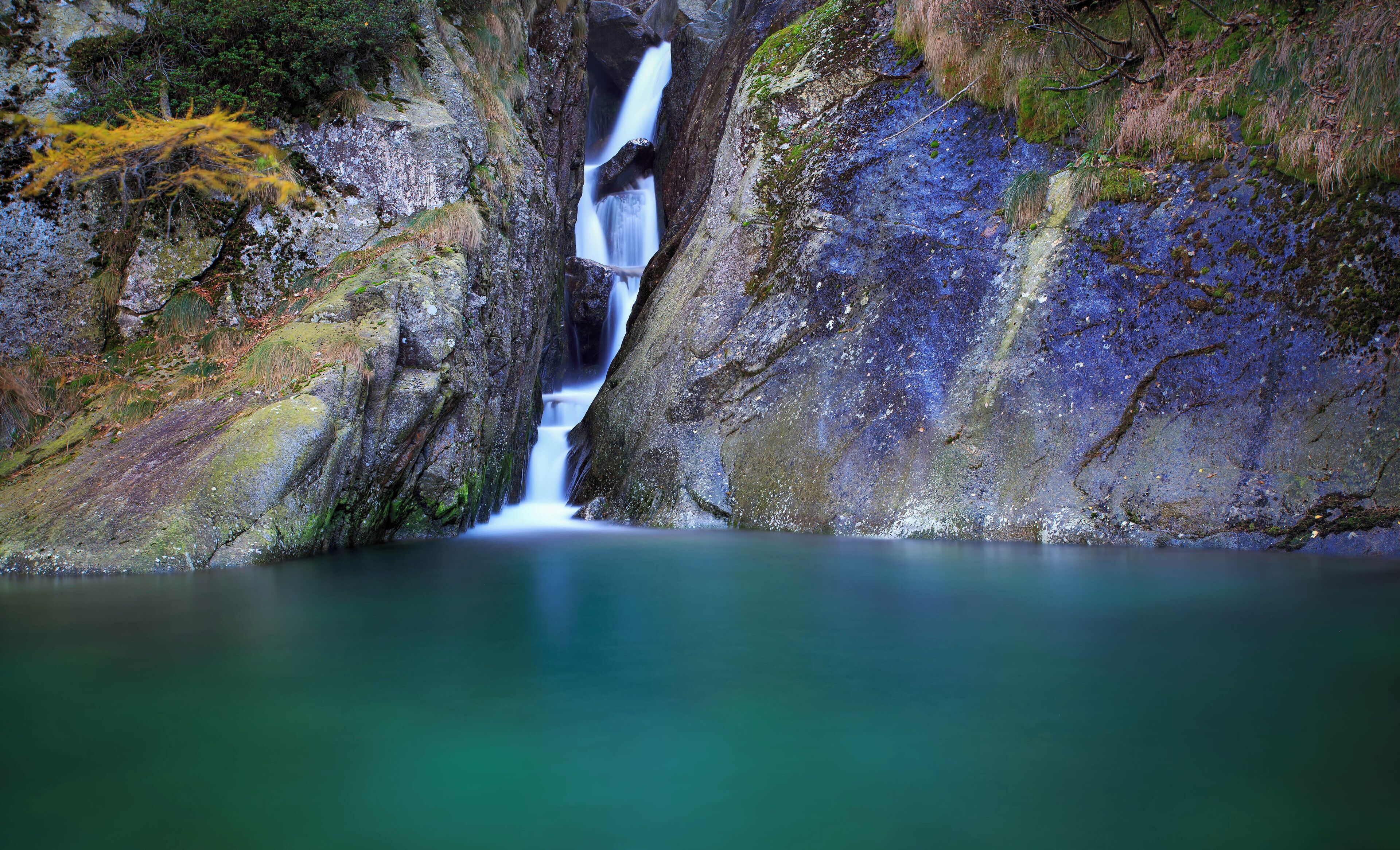 A waterfall cascading down a rocky cliff into a calm pool.