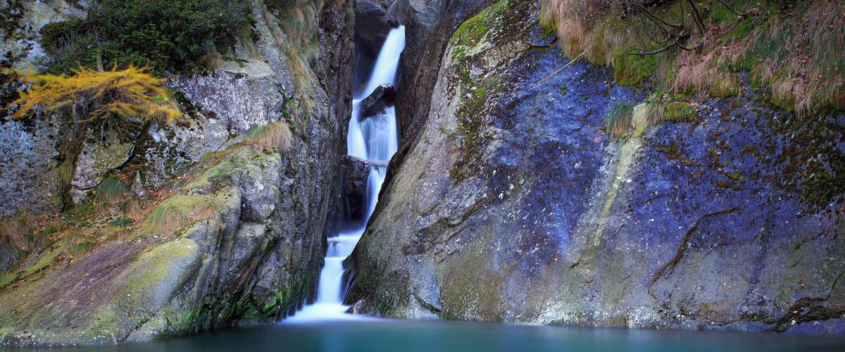 A waterfall cascading down a rocky cliff into a calm pool.