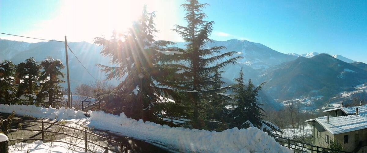 A snowy mountain landscape with a house and trees.