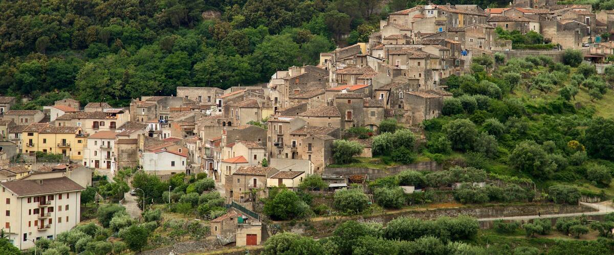 A hillside village with terracotta-roofed buildings nestled among lush greenery.