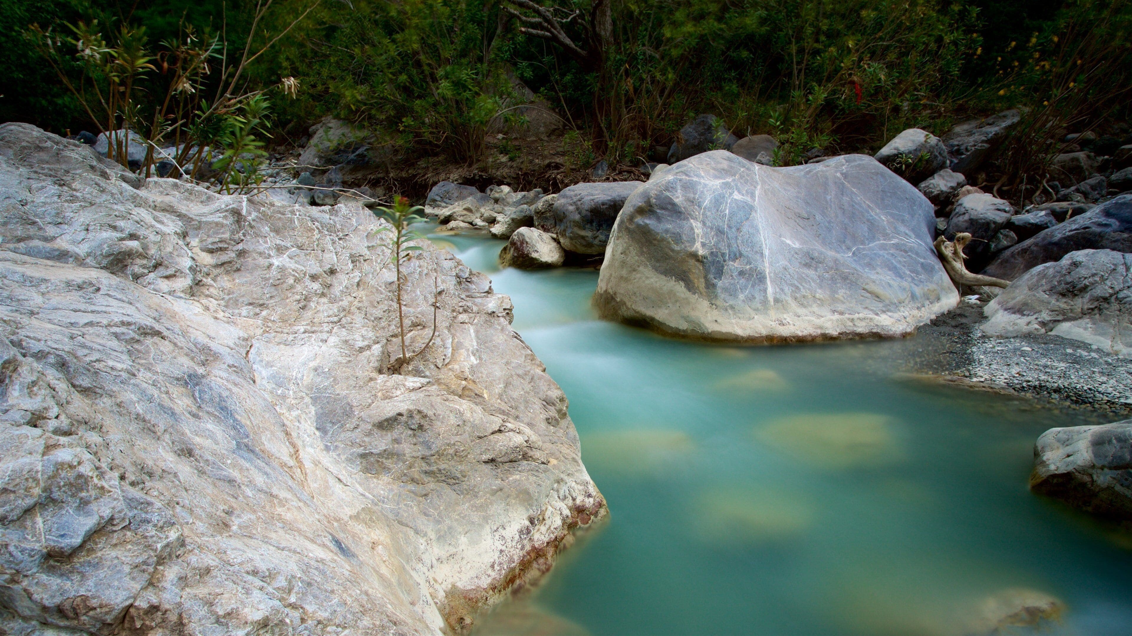 A river with clear water flowing around large rocks.