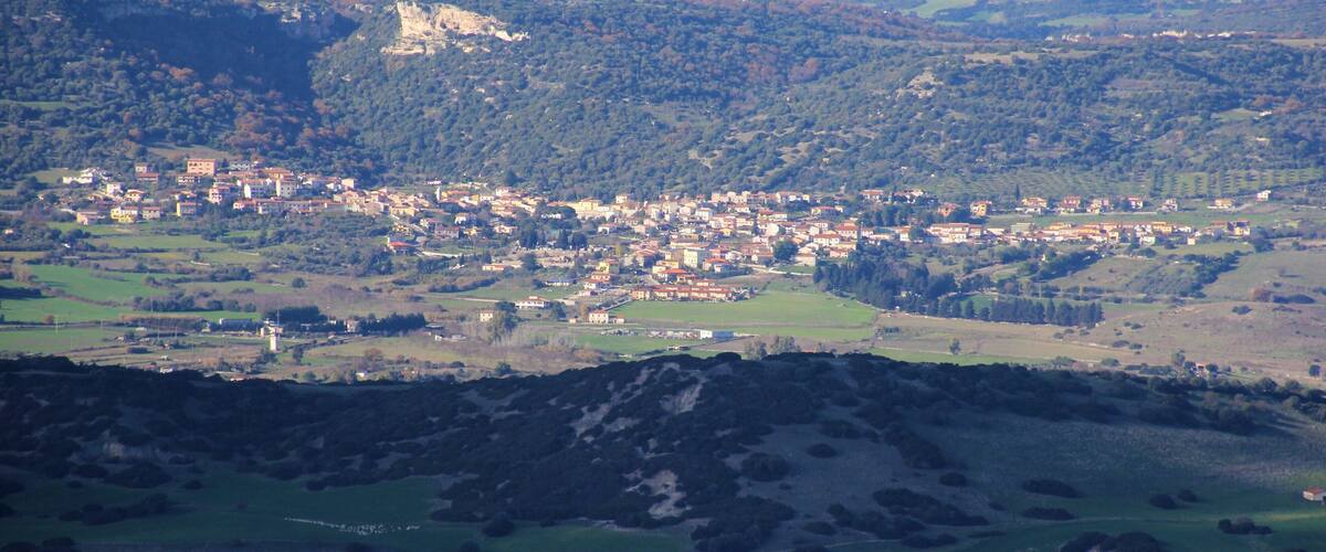 A town nestled in a valley with wind turbines in the background.