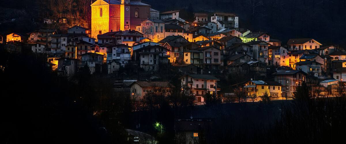 A village at dusk with a prominent church and residential buildings.