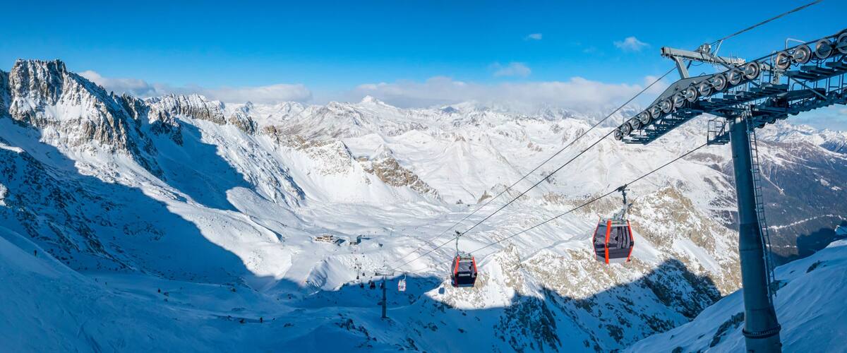 A snow-covered mountain with ski lifts and a clear blue sky.