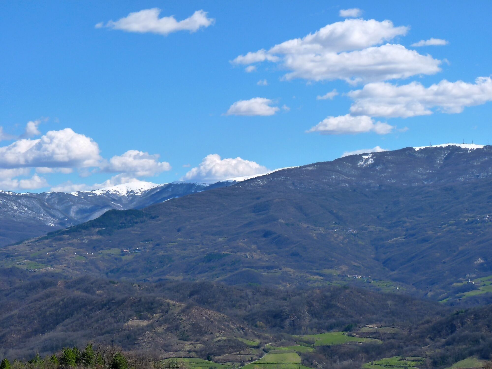 Eine gebirgige Landschaft mit schneebedeckten Gipfeln und grünen Tälern.