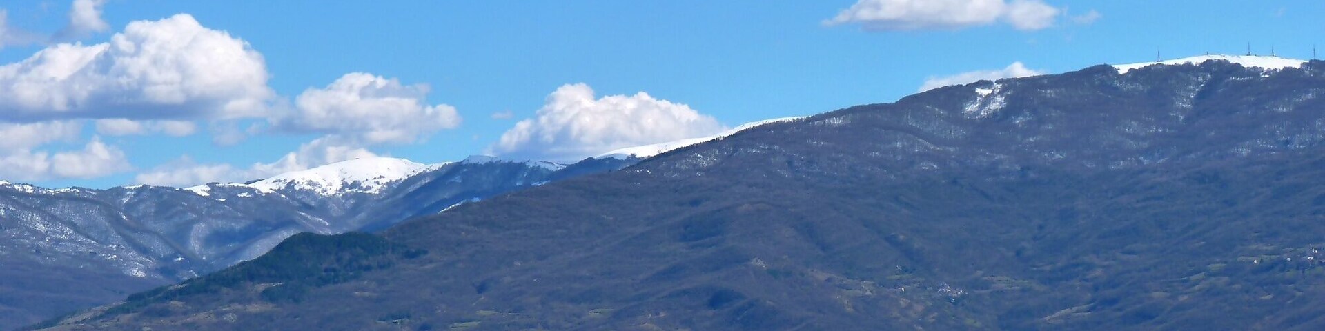 Un paisaje montañoso con picos nevados y valles verdes.