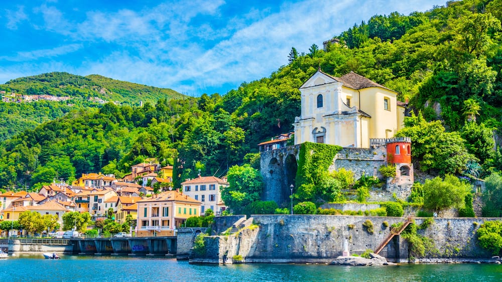 A coastal town with a prominent church on a hill, a stone wall, and a river.