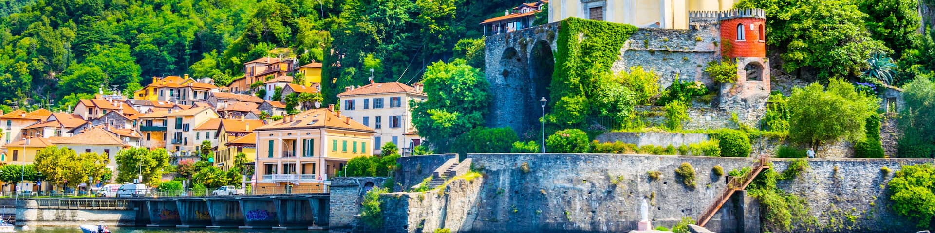 A coastal town with a prominent church on a hill, a stone wall, and a river.