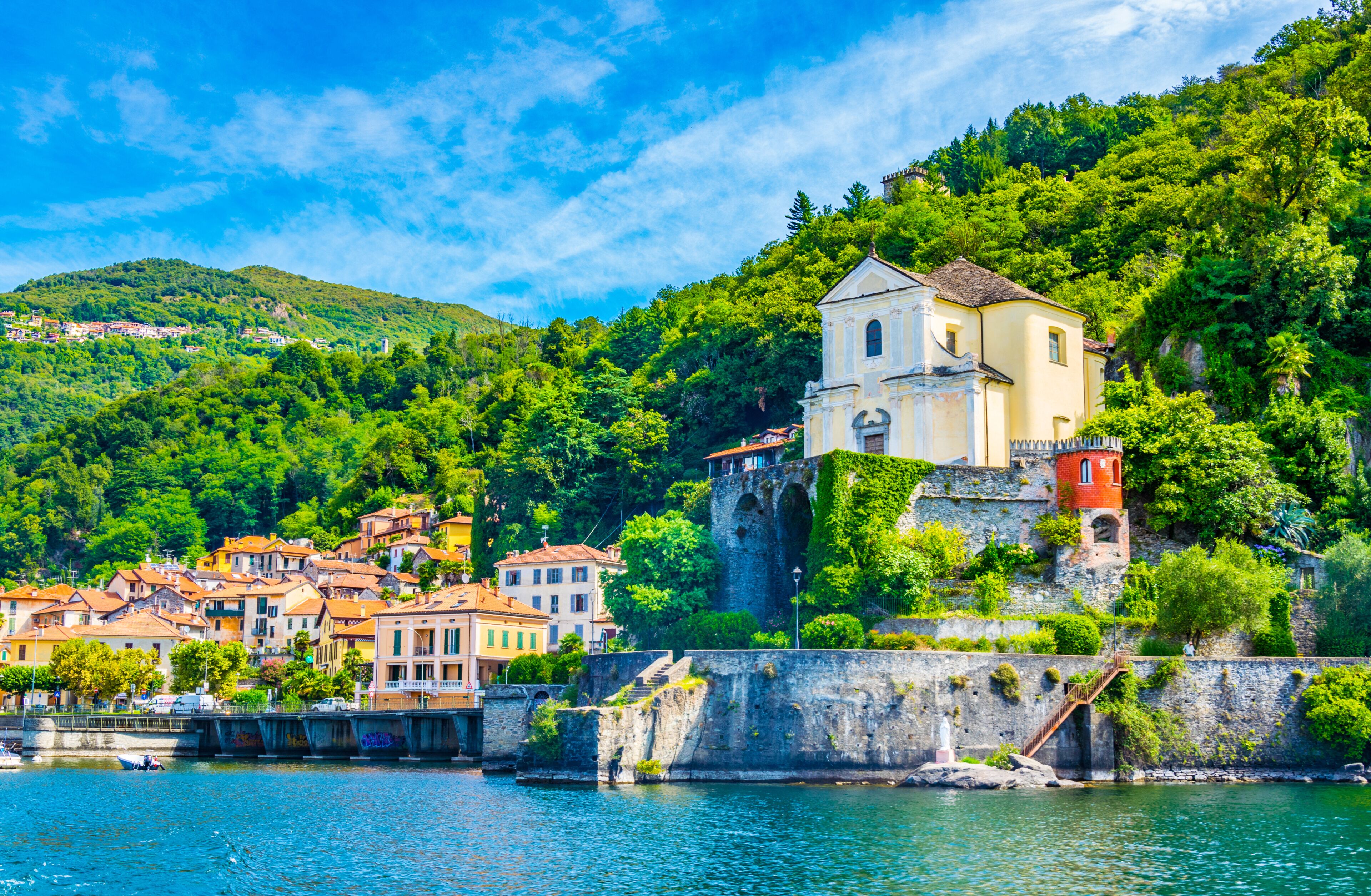 A coastal town with a prominent church on a hill, a stone wall, and a river.