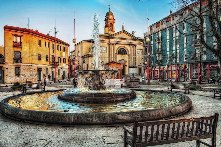 A historic fountain in a square surrounded by colorful buildings.