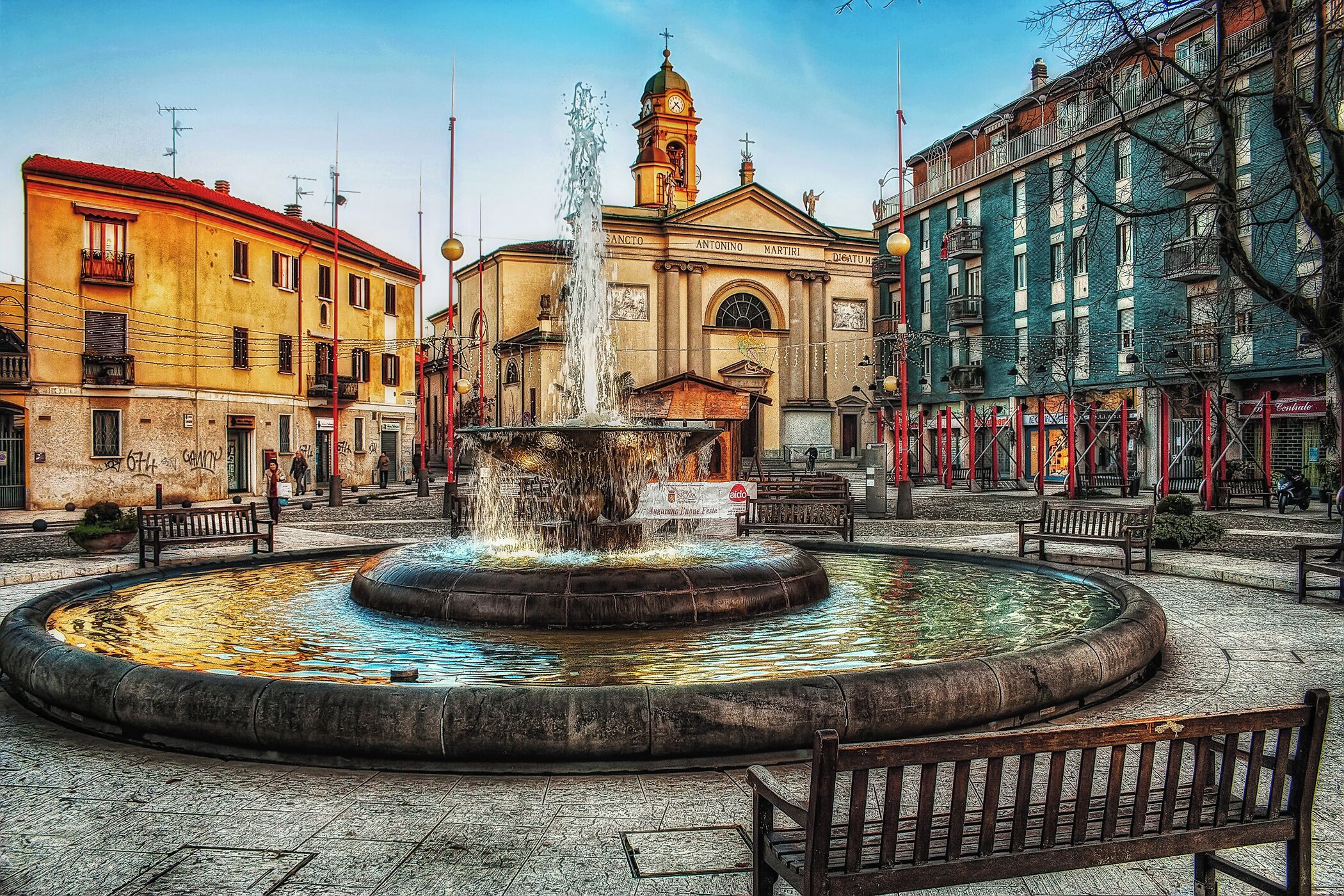 A historic fountain in a square surrounded by colorful buildings.