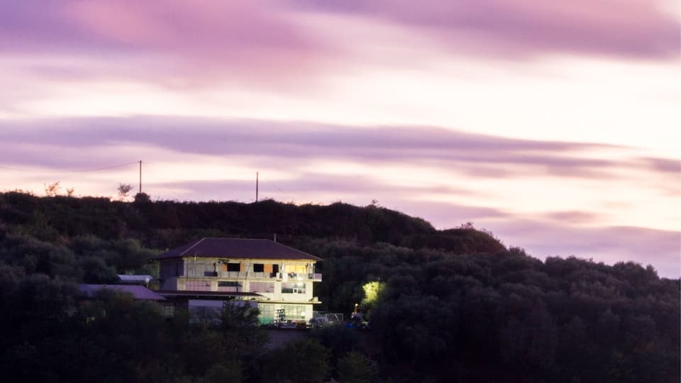 A two-story house on a hill with a purple sky.