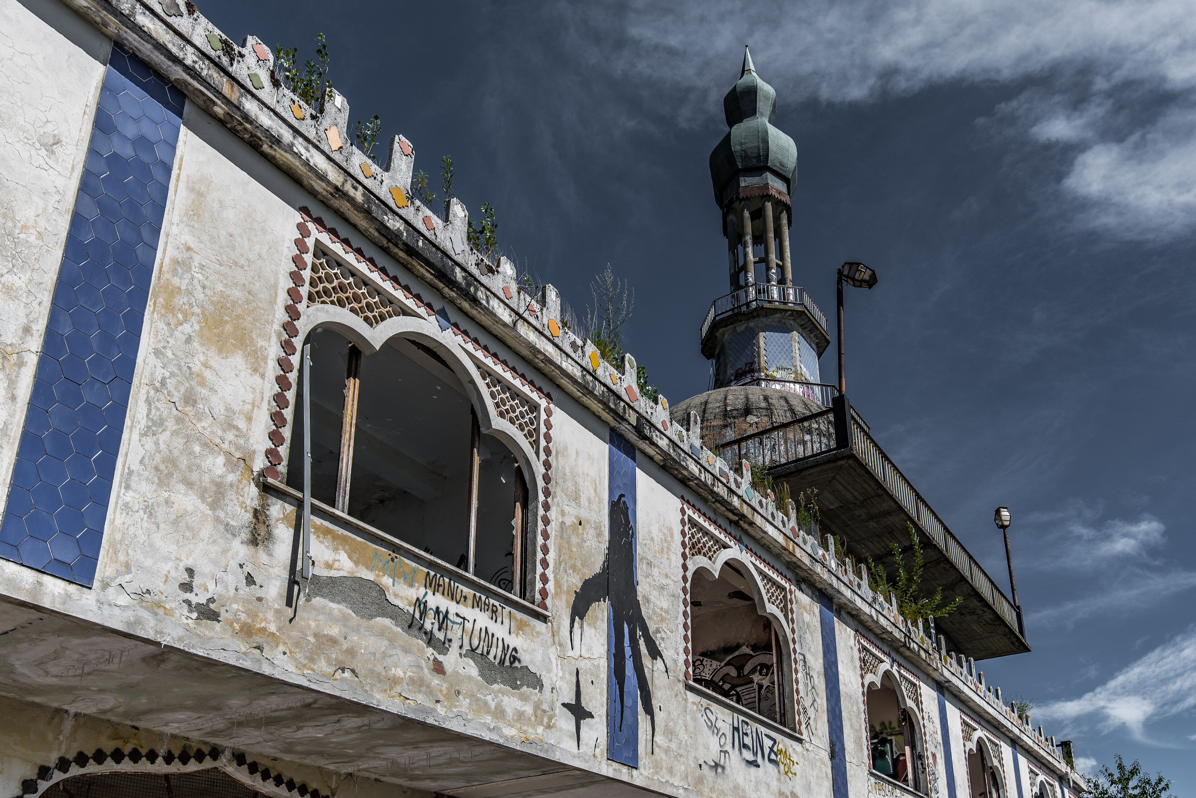 A historic building with intricate tile work, a prominent minaret, and graffiti.