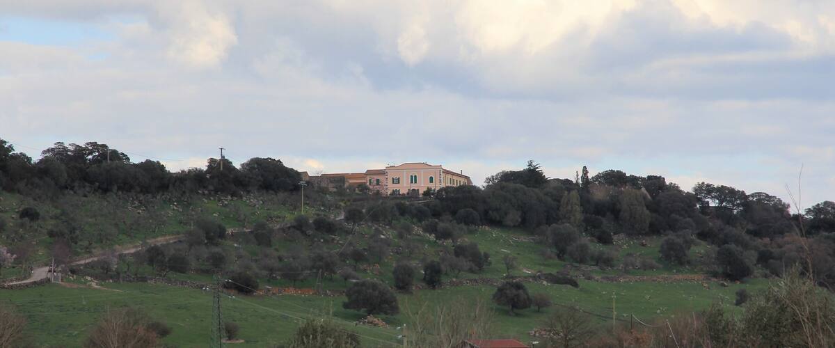 A large building on a hill with a cloudy sky.