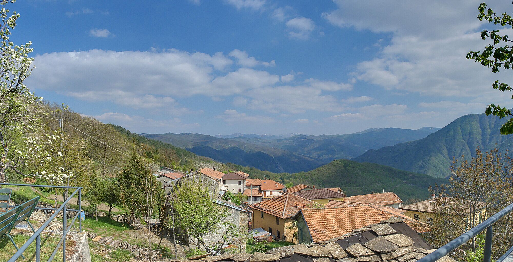 Un village niché dans une vallée, avec des maisons à étages et des montagnes en toile de fond.
