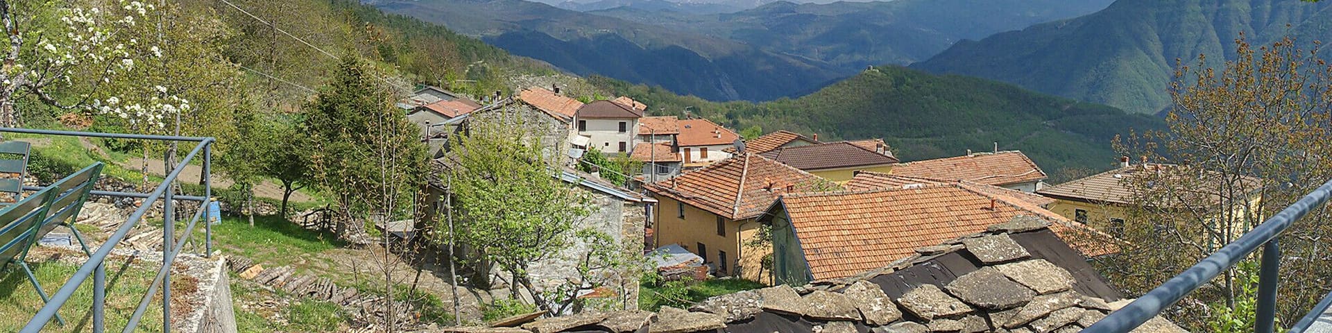 A village nestled in a valley with terraced houses and mountains in the background.