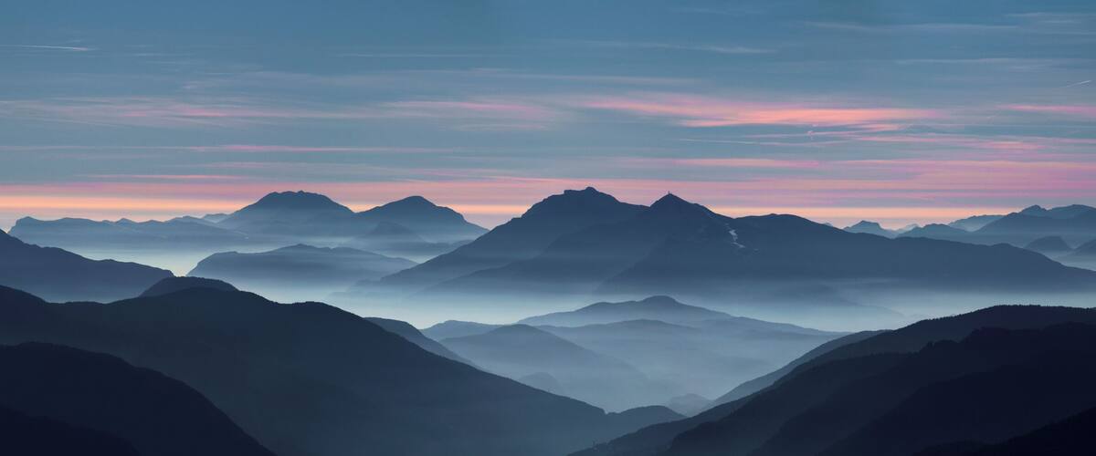 A mountain range with a pink and blue sky at sunrise or sunset.