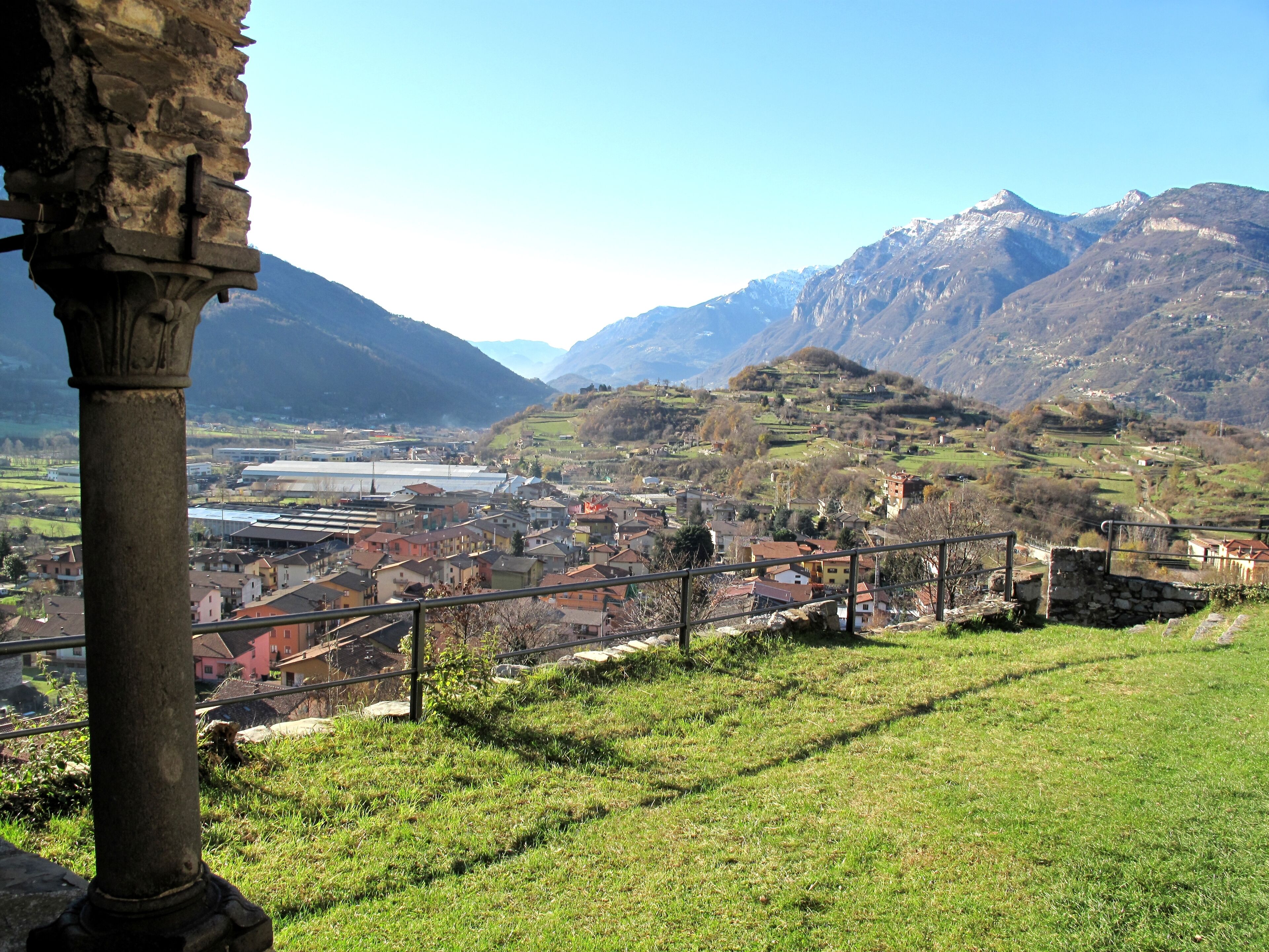 A mountainous landscape with a village, a stone column, and a river.