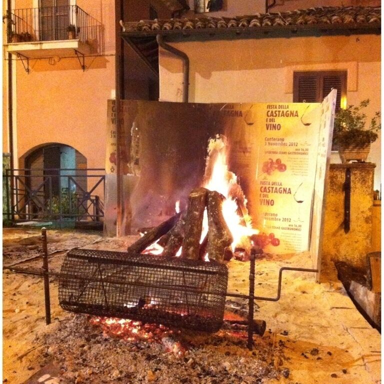 A fire burning in a metal container outdoors at night.