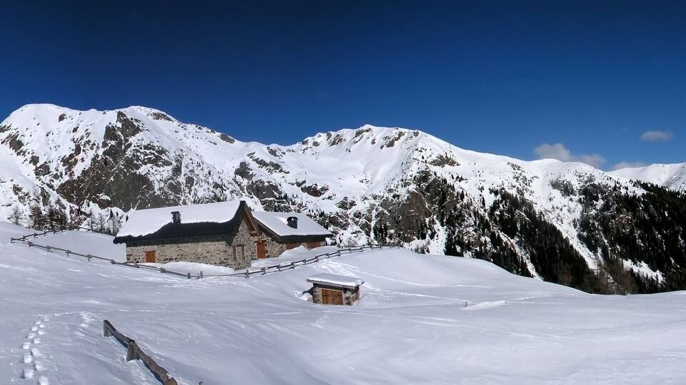 A snow-covered mountain landscape with a wooden cabin and a stone building.