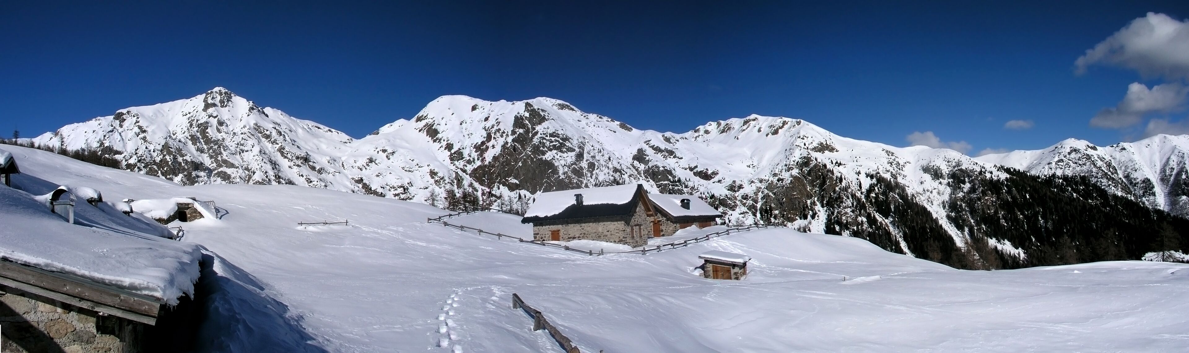A snow-covered mountain landscape with a wooden cabin and a stone building.