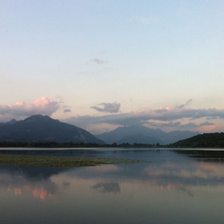 A calm lake with mountains in the background and a clear sky.