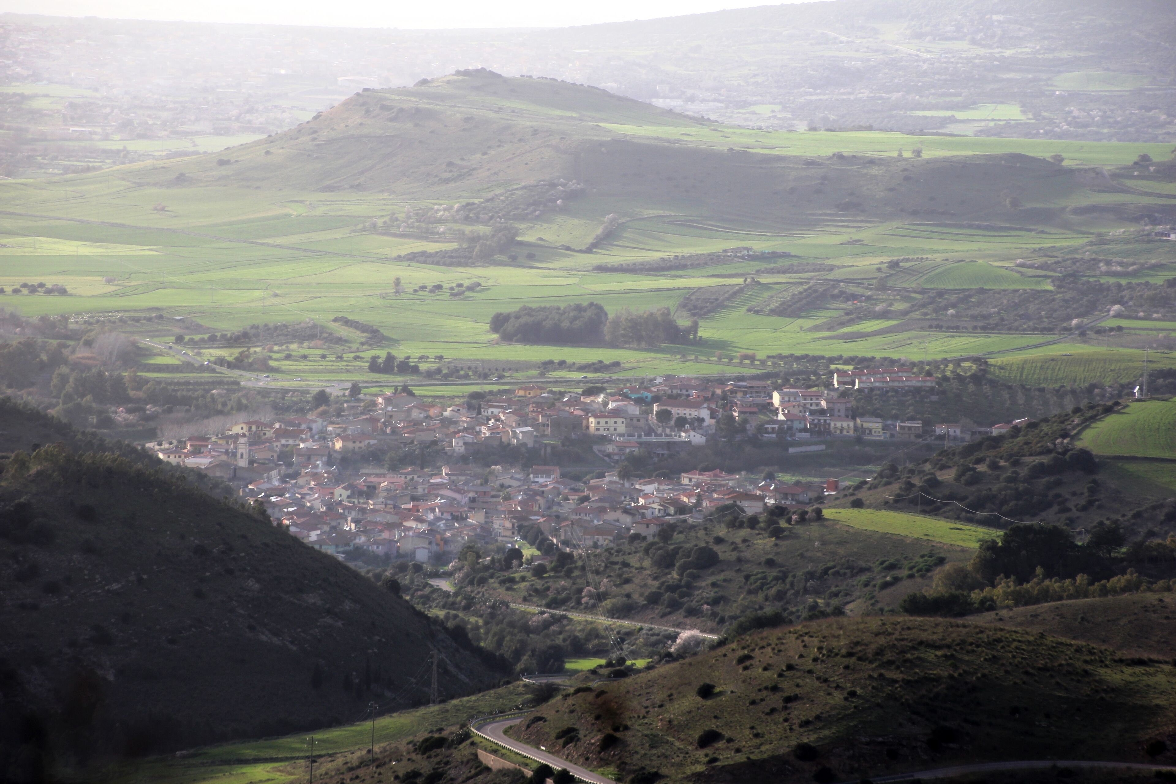 A valley with a town nestled among rolling hills and fields.