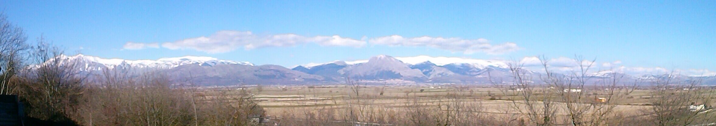 A mountainous landscape with snow-capped peaks and a clear sky.