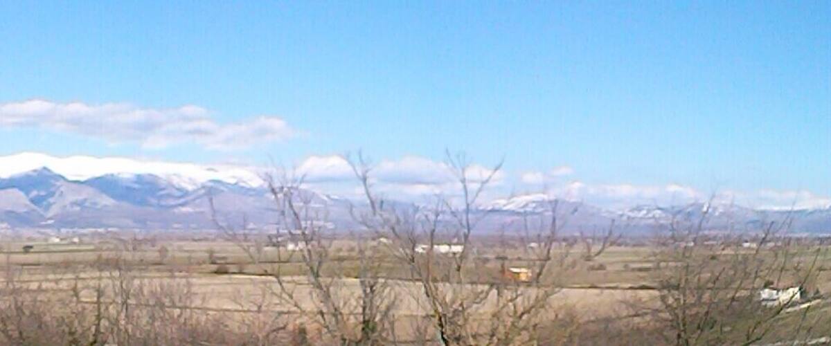 A mountainous landscape with snow-capped peaks and a clear sky.