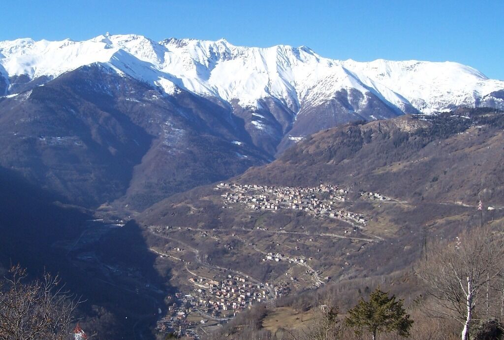 A snow-covered mountain range with a valley town nestled between the slopes.