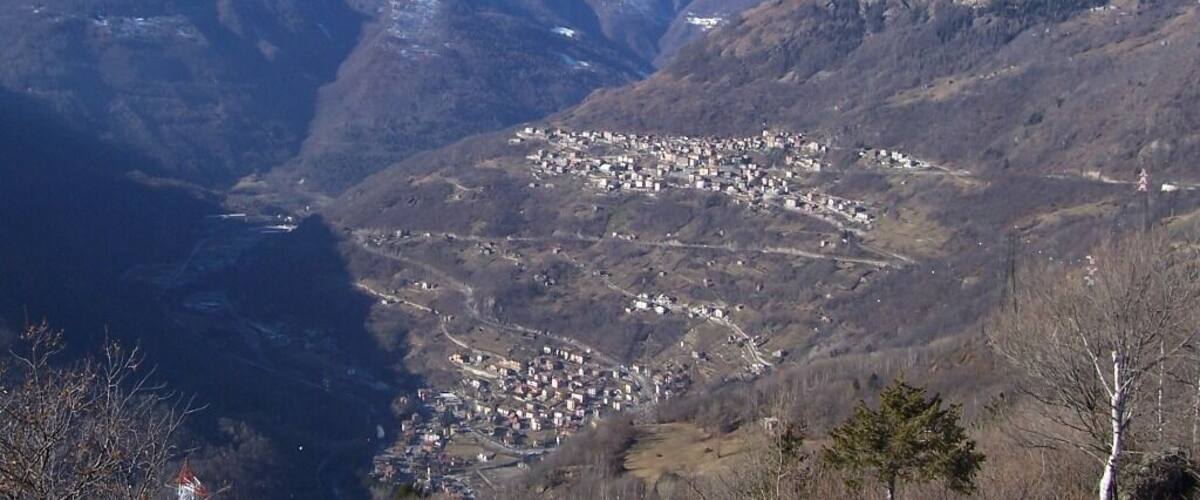 A snow-covered mountain range with a valley town nestled between the slopes.