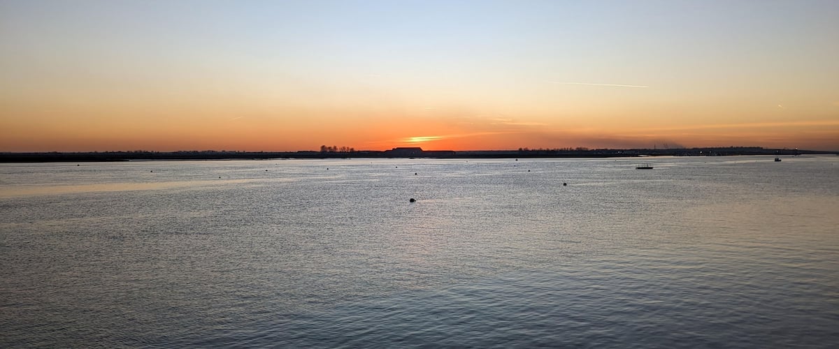 A calm river at sunset with a clear sky.