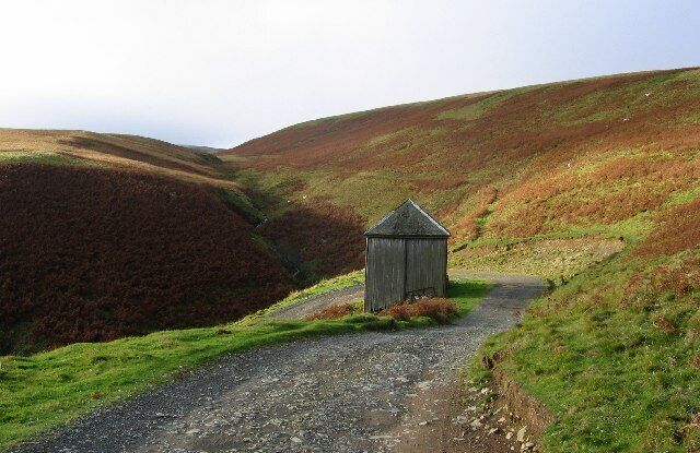 Road to Blackhope. Track to Blackhope farm. Speculation as to the building, probably a garage for times when the rest of the road to the farm was prone to snow? The photo was taken near the B7007 from Middleton to Innerleithen. At this point the Long Cleuch path emerges from the moors.