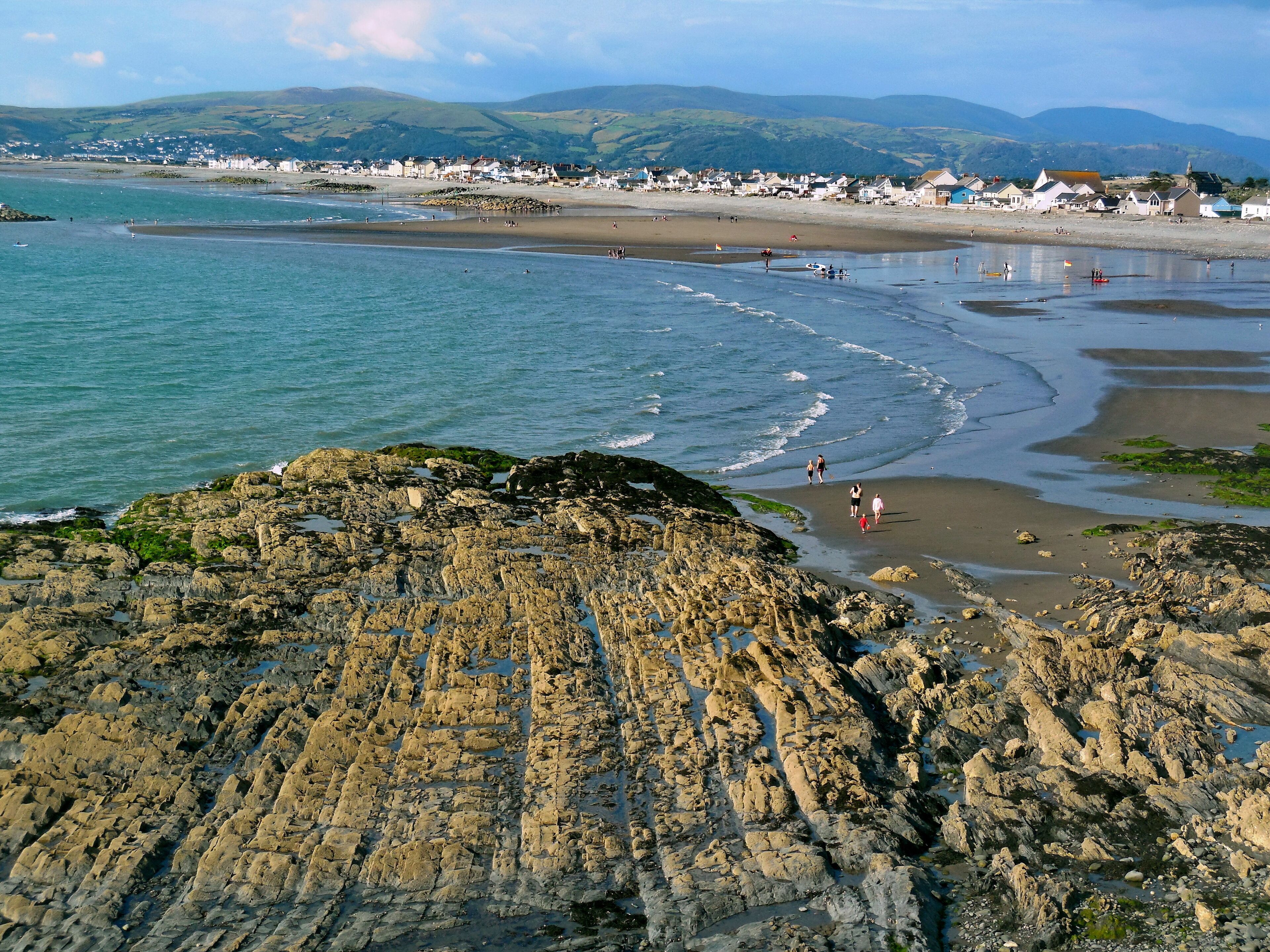 A coastal landscape with rocky shores, a sandy beach, and a village in the background.