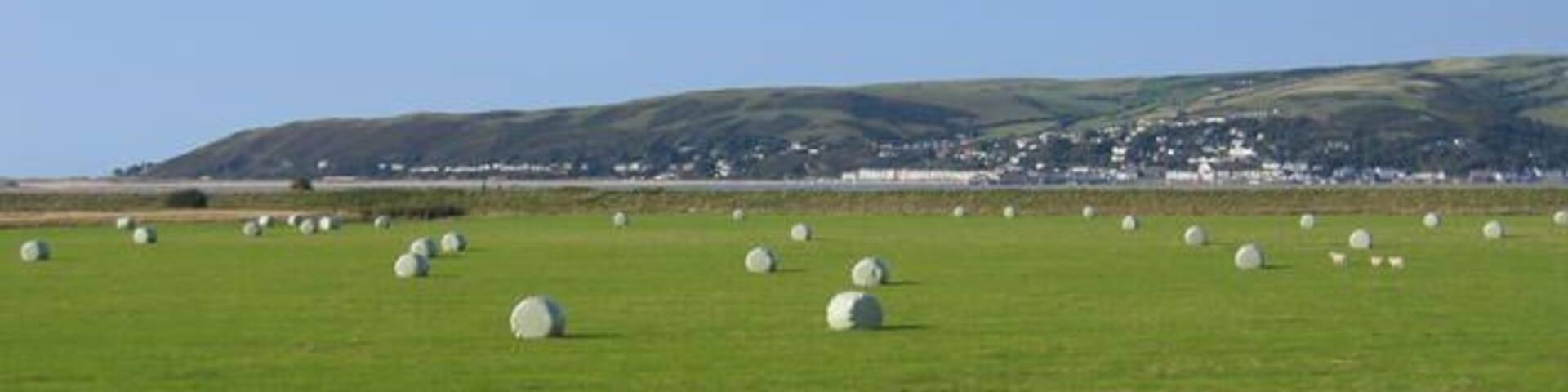 Dyfi estuary. Looking from an open train window across the low lying farmland and river estuary towards Aberdyfi on the far side of the water.