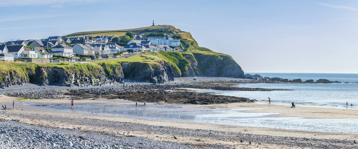 A coastal town with houses on a cliff, a beach, and the sea.